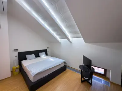 a white bedroom with a bed and a television at Loft-style& Modern Apartment in the center of Prague in Prague