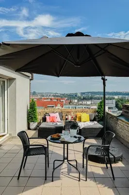 a patio with a table and chairs and an umbrella at Prague Days - Cozy Studio with Rooftop Terrace in hip Letná in Prague