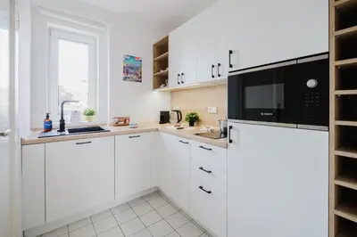 a kitchen with white cabinets and a microwave at Prague Days - Cozy Studio with Rooftop Terrace in hip Letná in Prague