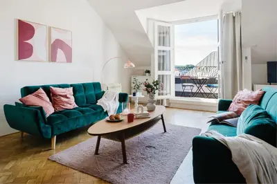 a living room with a green couch and a table at Prague Days - Loft with Terrace and Prague Castle View by Vltava River in Smíchov in Prague