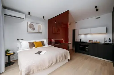a bedroom with a large white bed and a kitchen at Prague Days - Studio with Balcony and Garage Parking in Smíchov in Prague