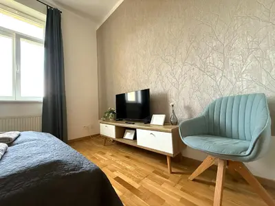 a bedroom with a blue chair and a television at Peaceful 1Bedroom Flat at Local side of the Center in Prague