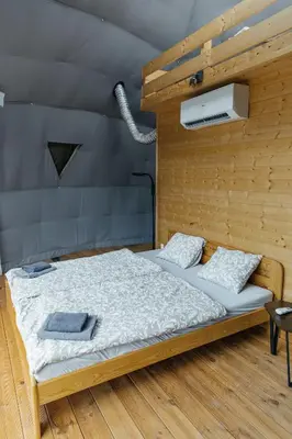 a wooden bed with two pillows on it in a room at Glamping Prague Louka in Prague