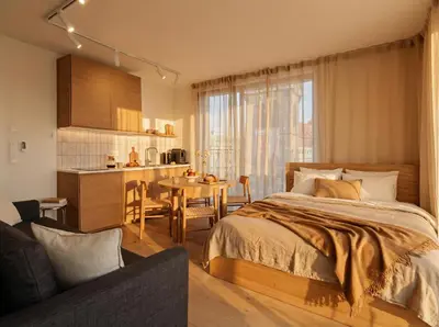 a bedroom with a bed and a table and a kitchen at Turnkey I Henry's Tower Apartments in Prague