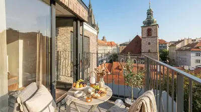 a balcony with a table and chairs and a clock tower at Turnkey I Henry's Tower Apartments in Prague