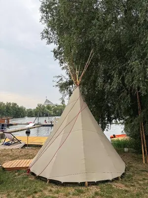 a teepee sitting on the grass next to a tree at Glamping TeePee in Brandýs nad Labem-Stará Boleslav