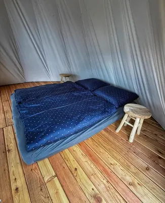 a bedroom with a blue bed and a stool at Glamping TeePee in Brandýs nad Labem-Stará Boleslav