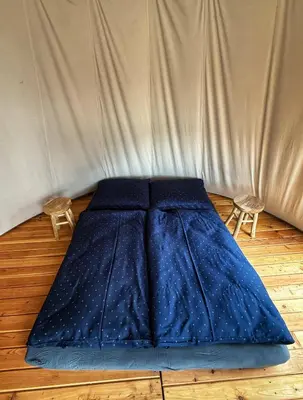 a blue bed in a room with two chairs at Glamping TeePee in Brandýs nad Labem-Stará Boleslav