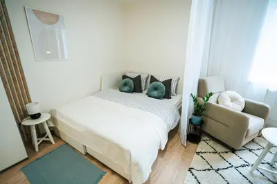 a bedroom with a white bed and a chair at Blue Apartment - Vršovice in Prague