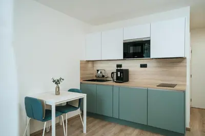 a kitchen with blue cabinets and a white table and chairs at Blue Apartment - Vršovice in Prague