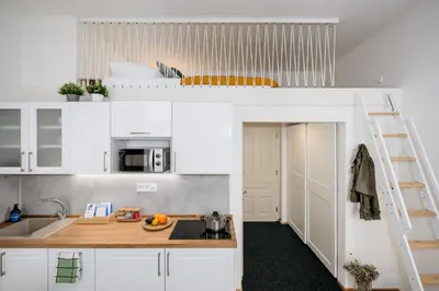 a kitchen with white cabinets and a loft bed at Prague Days - Fully Equipped Studio near Wenceslas Square in Prague