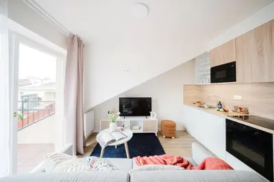 a white living room with a couch and a tv at Prague Days - Modern Apartments with AC near King's Park in Prague