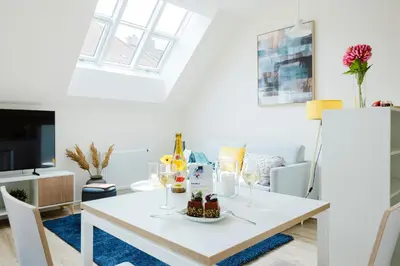 a white table with a plate of food on it in a living room at Prague Days - Modern Apartments with AC near King's Park in Prague