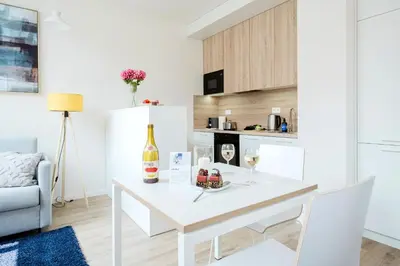 a white kitchen with a white table and chairs at Prague Days - Modern Apartments with AC near King's Park in Prague