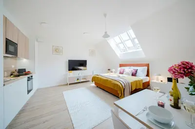 a bedroom with a bed and a kitchen with a table at Prague Days - Modern Apartments with AC near King's Park in Prague