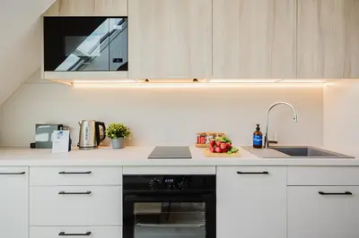 a kitchen with white cabinets and a black oven at Prague Days - Bright Apartments with AC near Vyšehrad Castle in Prague