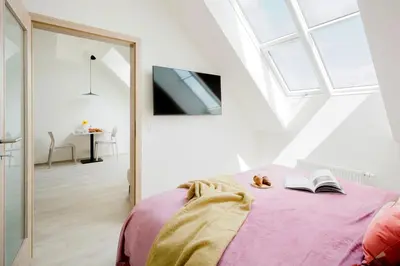 a bedroom with a bed with a book and a mirror at Prague Days - Bright Apartments with AC near Vyšehrad Castle in Prague