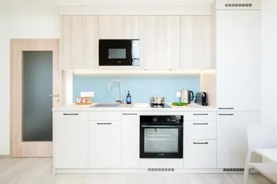a white kitchen with a sink and a microwave at Prague Days - Bright Apartments with AC near Vyšehrad Castle in Prague