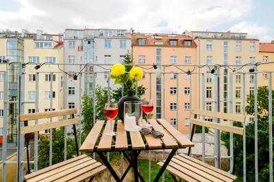 a table with two glasses of wine on a balcony at Prague Days - Bright Apartments with AC near Vyšehrad Castle in Prague
