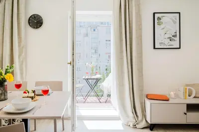 a white dining room with a table and a window at Prague Days - Bright Apartments with AC near Vyšehrad Castle in Prague