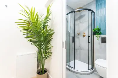 a bathroom with a glass shower and a plant at Rentero Central Loft Apartment in Prague