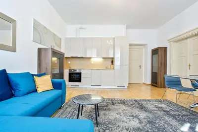 a living room with a blue couch and a kitchen at Rhapsody in Prague
