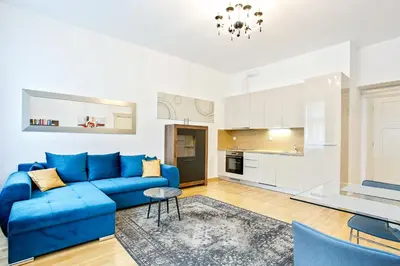 a living room with a blue couch and a kitchen at Rhapsody in Prague