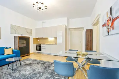 a kitchen and living room with a glass table and blue chairs at Rhapsody in Prague