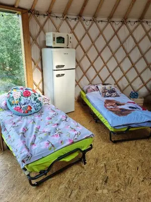 a room with two beds and a refrigerator in a yurt at 02 JURTA hnědá v jablečném sadu