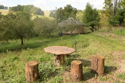 a wooden table sitting in the middle of a field at 02 JURTA hnědá v jablečném sadu