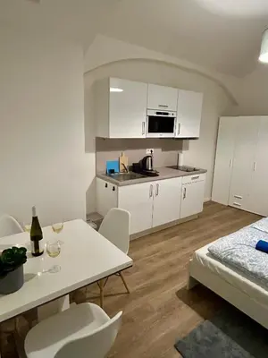 a kitchen with white cabinets and a table and chairs at Cozy Budget Studio by F&S in Prague