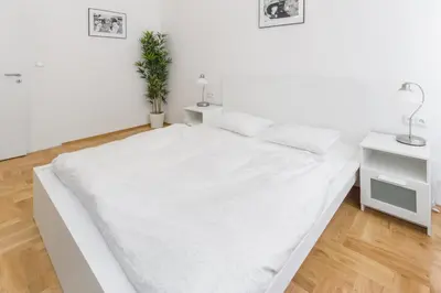 a white bedroom with a white bed and two tables at Apartment Jindrisska in Prague