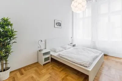 a white bedroom with a bed and a potted plant at Apartment Jindrisska in Prague