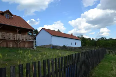 a white house with a red roof behind a fence at Country house - Slapy/Pazderny in Žďár