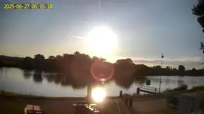 a sunset over a lake with the sun in the sky at Camp in Horní Počaply
