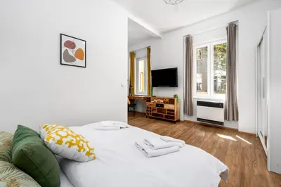 a white bed in a room with a window at Botanica Suite Prague in Prague