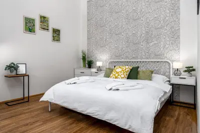a bedroom with a white bed and a wall at Botanica Suite Prague in Prague
