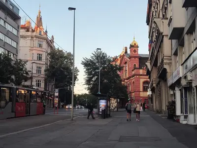 a city street with people walking on the sidewalk and a bus at Prague-2 Vinohrady Apartment in Prague