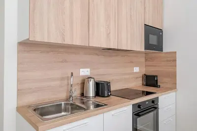 a kitchen with a stainless steel sink and wooden cabinets at Blueground Holešovice balcony nr Vltava PRG-55 in Prague