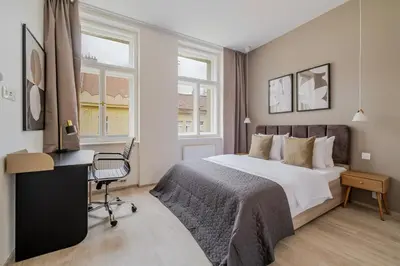a bedroom with a bed and a desk and windows at Blueground Nusle city view nr Vysehrad PRG-73 in Prague