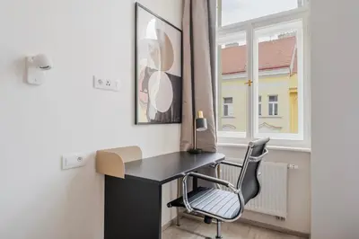 a desk and a chair in a room with a window at Blueground Nusle city view nr Vysehrad PRG-73 in Prague