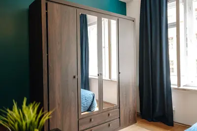 a wooden cabinet with a mirror in a bedroom at Central Riverside 2BD Apt by Vltava & Theater in Prague