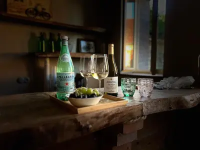 two bottles of wine and a bowl of fruit on a counter at Statek Pazderna