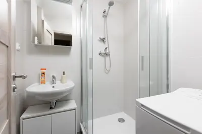 a white bathroom with a shower and a sink at Apartment - 2 bedrooms, kitchen, close to metro in Prague
