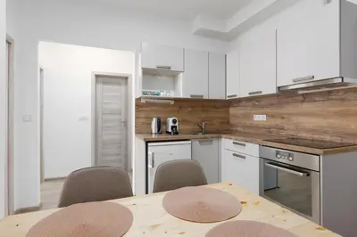 a kitchen with white cabinets and a table with chairs at Apartment - 2 bedrooms, kitchen, close to metro in Prague