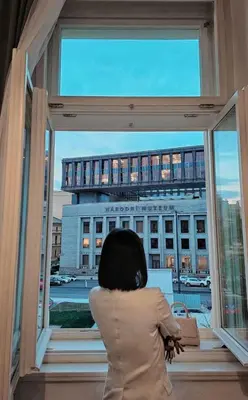a child looking out of a window at a building at Historic Cozy Apartment with National Museum View in Prague