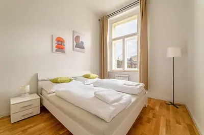 a white bed in a room with a window at Historic Cozy Apartment with National Museum View in Prague