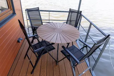 a table with chairs and an umbrella on a boat at Houseboat Daisy in Prague