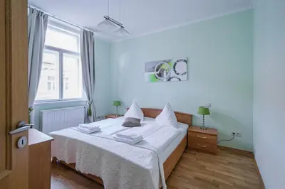 a bedroom with a bed with white sheets and a window at Riverside Ruterra Apartment in Prague