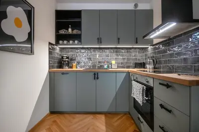 a kitchen with blue cabinets and a tile wall at Atelier in the Heart of Karlín in Prague
